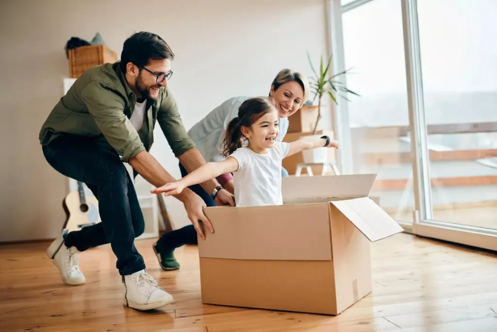 Hija feliz divirtiéndose con sus padres mientras se mudan a un nuevo apartamento
